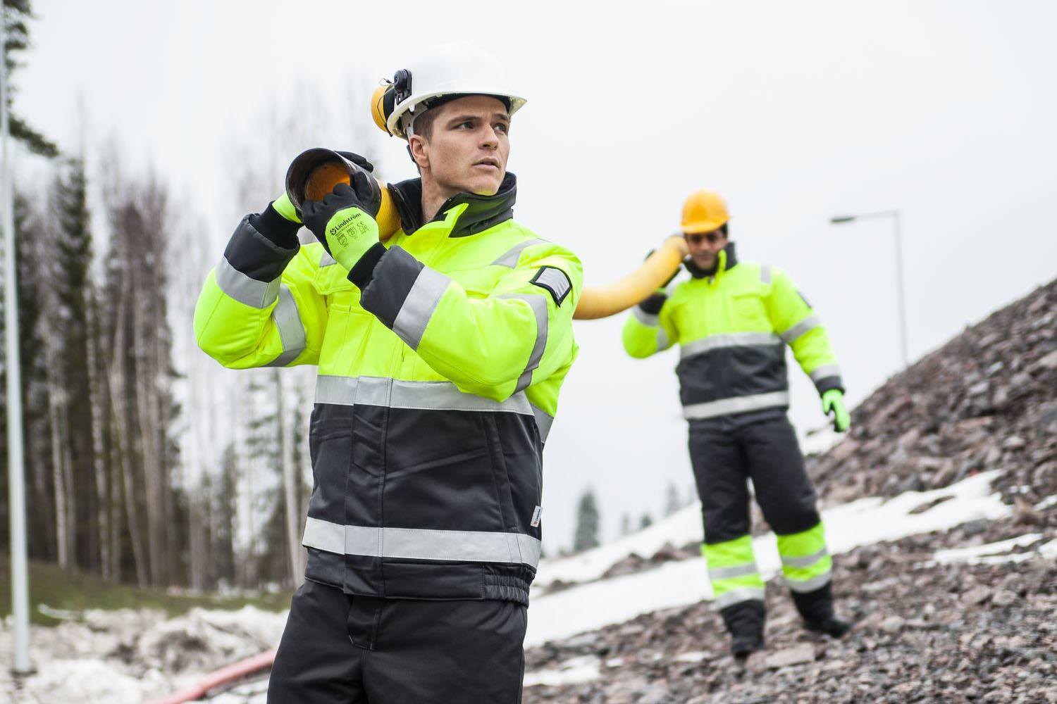 2 workmen wearing construction clothing working in cold conditions