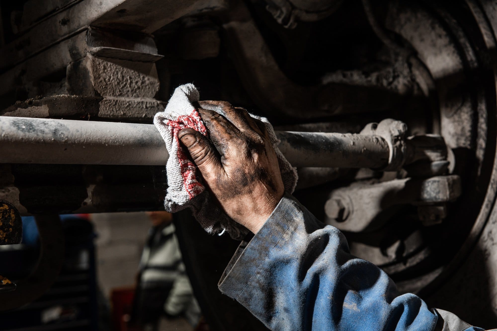 mechanic cleaning underneath car with industrial cleaning rag
