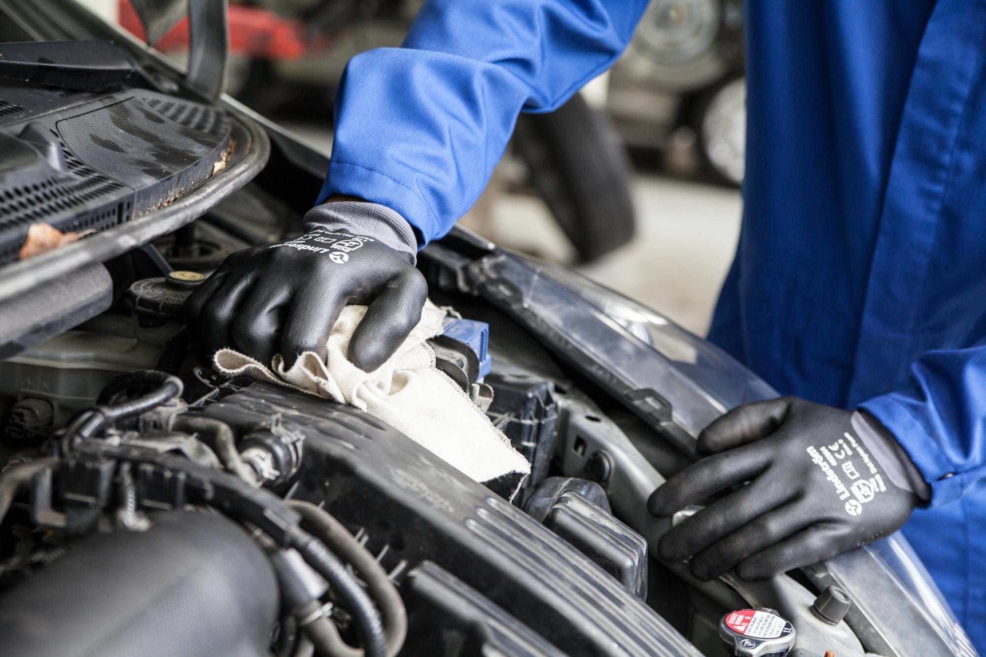 mechanic cleaning top of engine with cleaning cloth