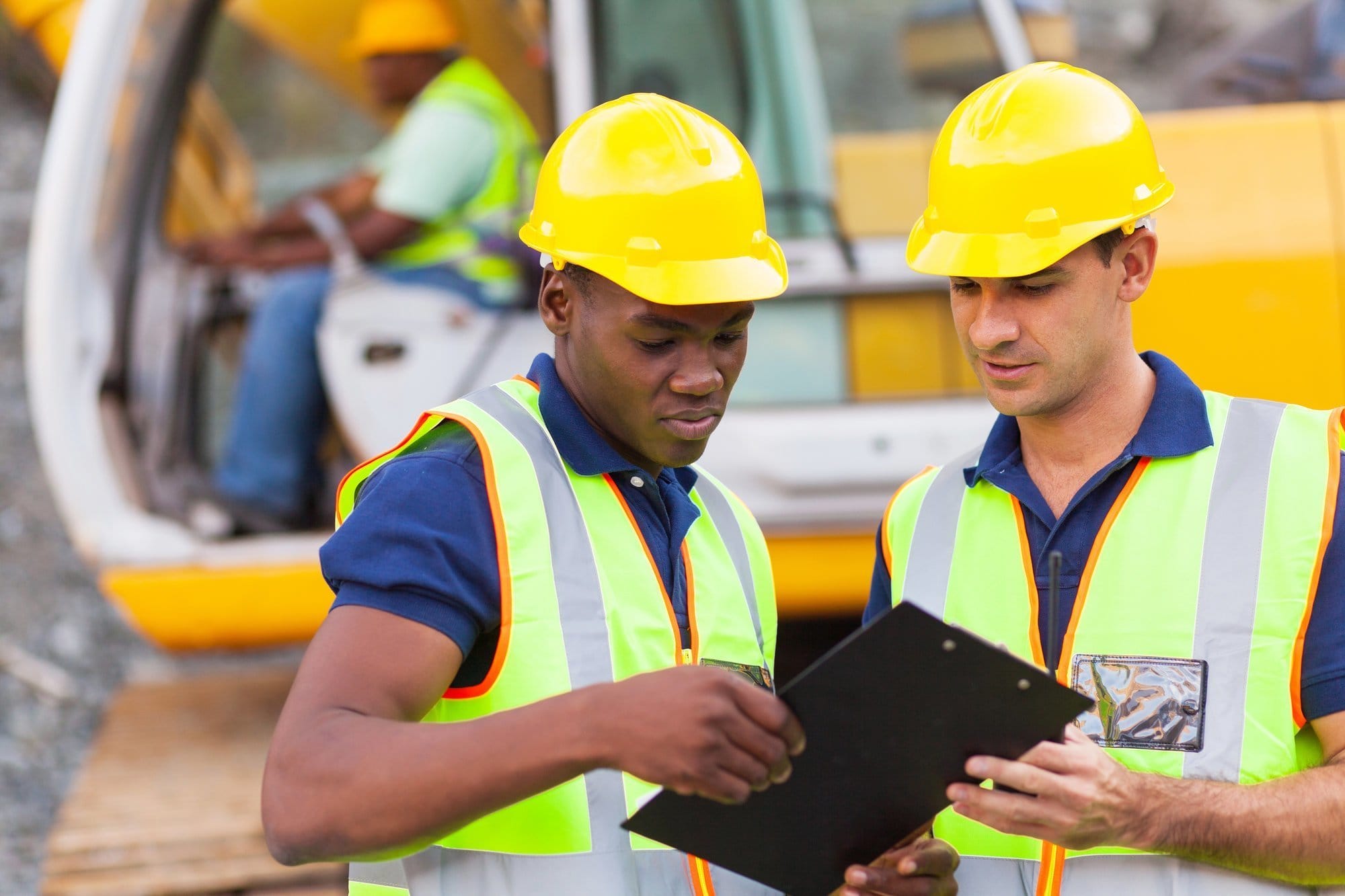 two construction workers wearing hi-vis vests and looking at a clipboard