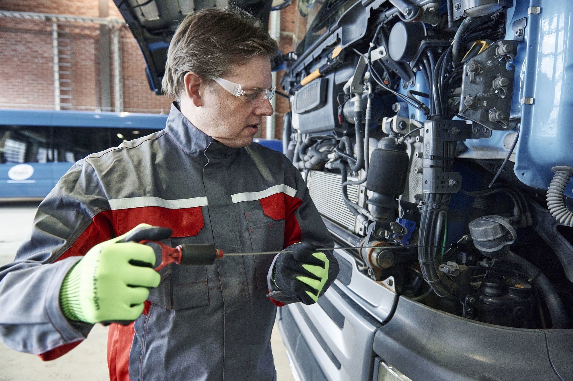 mechanic working on a car wearing blue and red mechanic overalls