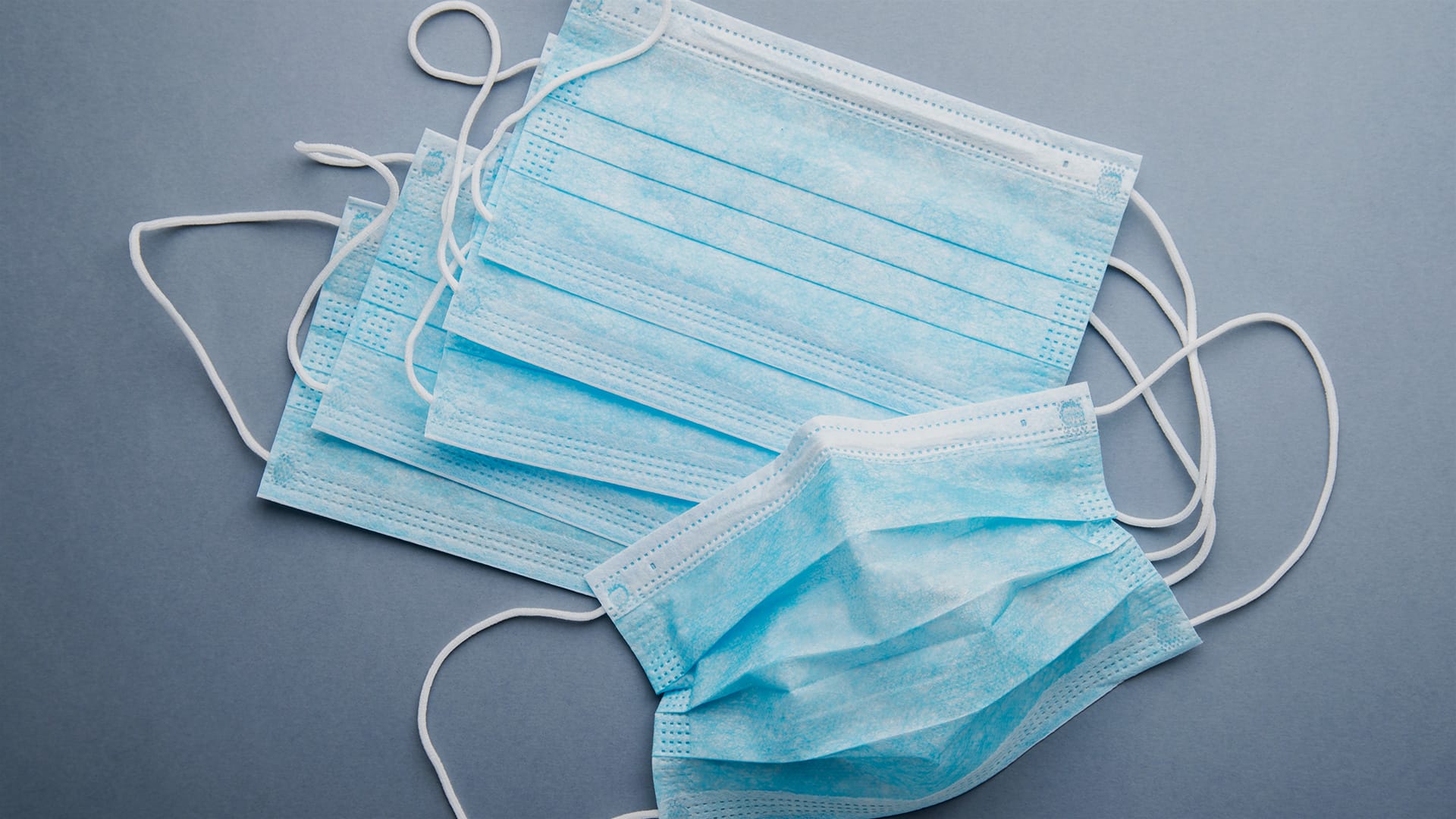 Blue disposable face masks on grey background