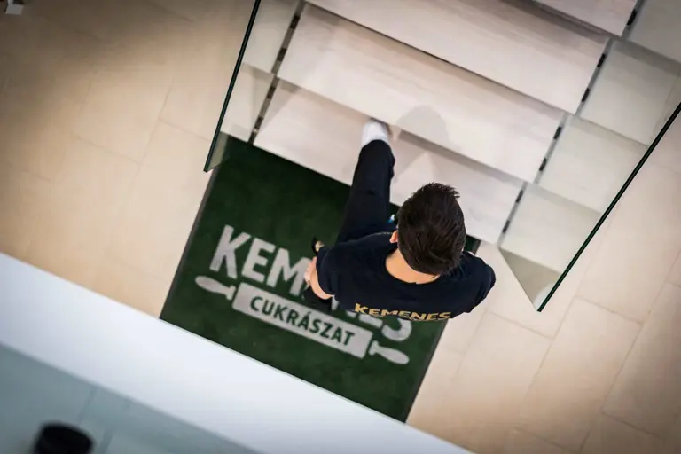 Kemenes darbuotojas prie įmonės logotipu pažymėto įėjimo kilimėlio