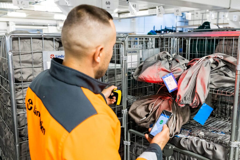 Pracovník Lindström načítá RFID čipy na pracovních oděvech při evidenci a přípravě servisního závozu.